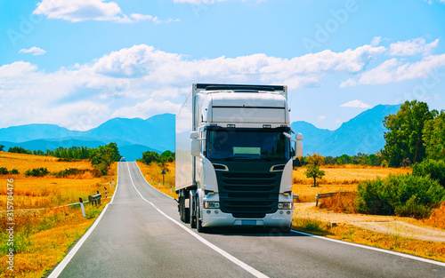 Truck on road at Carbonia in Sardinia Island, Italy summer. Truck trailer driving on motorway at highway. Lorry transport delivering some freight cargo. Cagliari province. Mixed media.