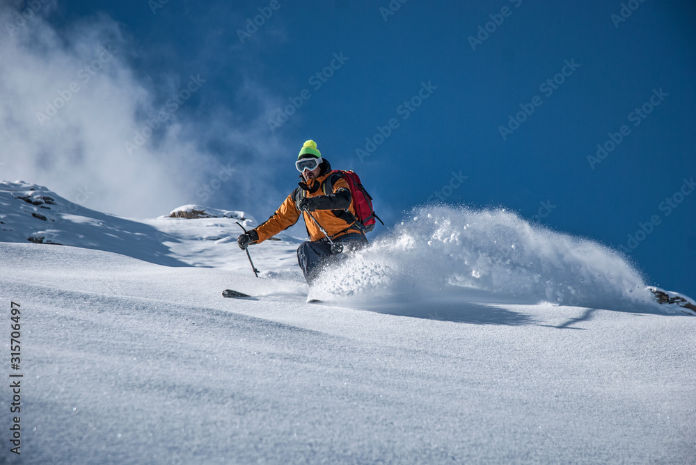 Sciatore su pendio in neve polverosa
