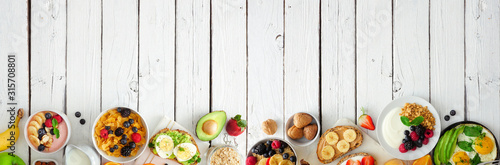 Healthy breakfast food banner with bottom border. Table scene with fruit, yogurt, smoothie bowl, nutritious toasts, cereal and egg skillet. Top view over a white wood background. Copy space.