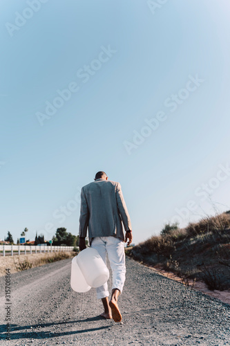 Young man holding empty water cans walking on dirt track photo