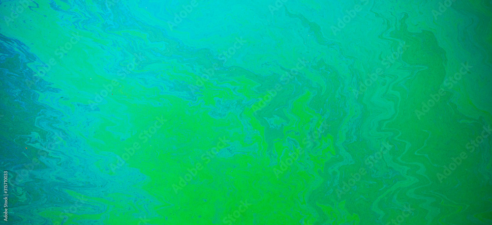 Blue, green, yellow color oil patterns on the surface of the water
