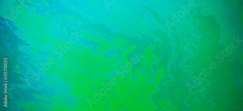 Blue, green, yellow color oil patterns on the surface of the water