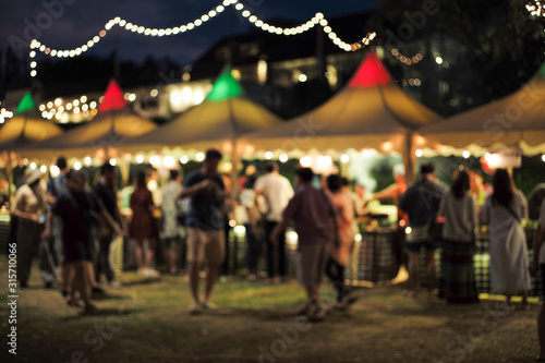 Blurred motion people walk in the food festival at night with decorative bokeh light in background photo