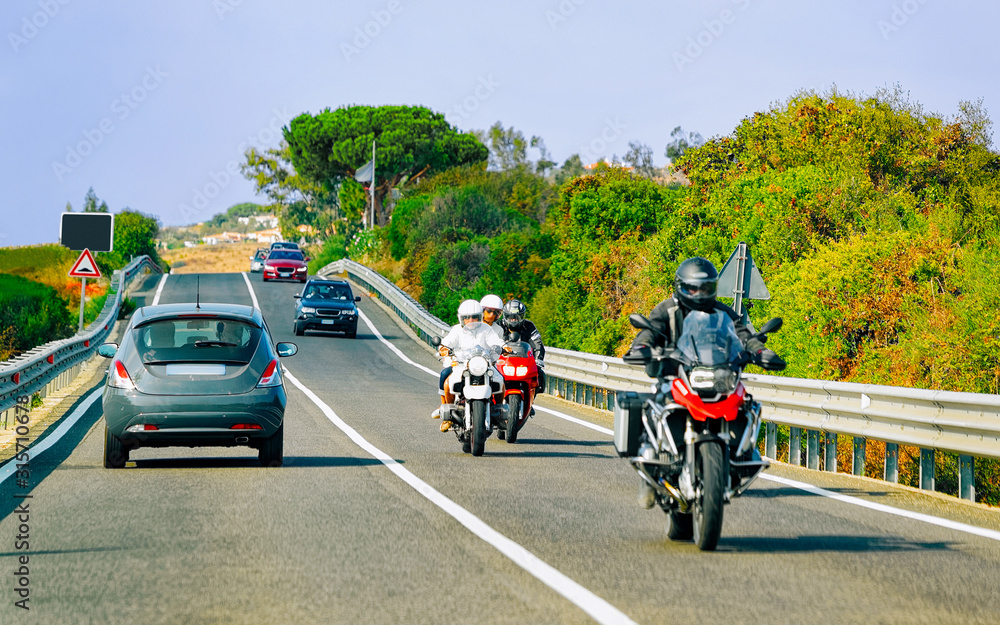 Bicycles and car on road at in Sardinia Island in Italy in summer. Bikers driving scooter on highway of Europe. Men riding bikes on motorway. Olbia province. Mixed media. Bicycles and car on road at in Sardinia Island in Italy in summer. Bikers driving scooter on highway of Europe. Men riding bikes on motorway. Olbia province. Mixed media.