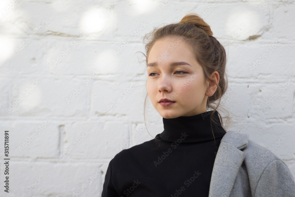 Portrait of young caucasian woman looking aside with calm look on white brick background Portrait of young caucasian woman looking aside with calm look on white brick background