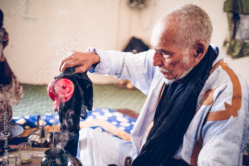 Senior man in Smara refugee camp preparing tea, Tindouf, Algeria photo