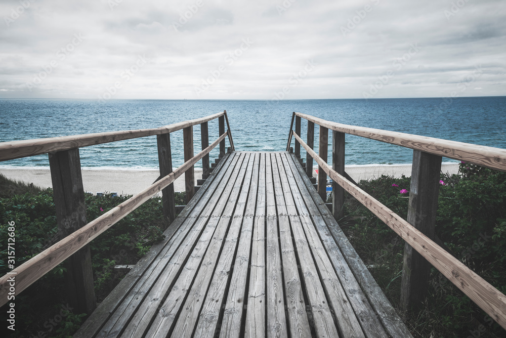Wooden footpath towards sea on Sylt island on a rainy summer day Wooden footpath towards sea on Sylt island on a rainy summer day
