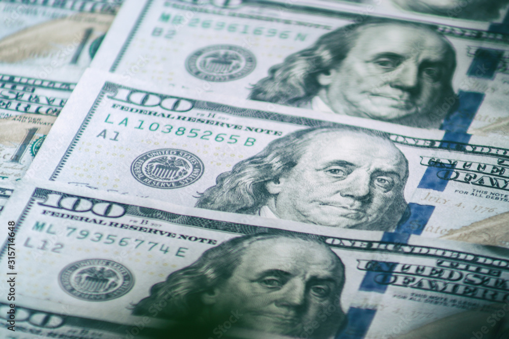 Background of one hundred dollar bills. Benjamin Franklin on USA money banknote. American dollars banknotes background. US dollars pattern. 100 dollars. Close-up selective focus Background of one hundred dollar bills. Benjamin Franklin on USA money banknote. American dollars banknotes background. US dollars pattern. 100 dollars. Close-up selective focus