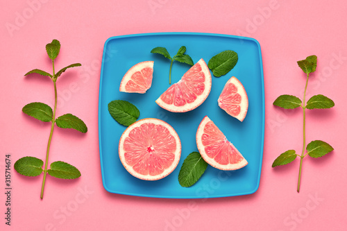 Orange fresh fruit with green mint leaves on plate. Healthy vegan food organic Concept. Creative citrus Flat lay. Trendy fashion Style. Minimal Art. Summer pink bright Color.