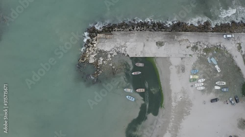 Aerial top down  footage of colorful fishing boats moored near the shore of Bolata cove on Black sea, Bulgaria. Drone panning from right to left photo