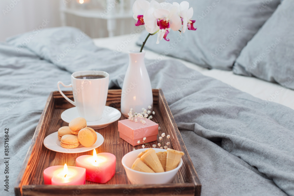 Coffee, sweets,  candles, flowers and girt on wooden tray on bed. Concept with Valentines day