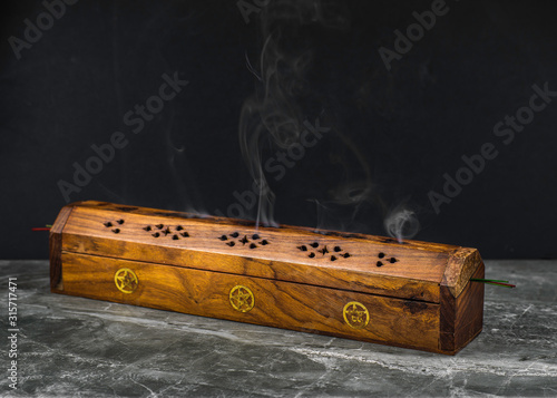 Obraz na plátně A long wooden incense burner holder on a grey stone tile base with black backgro