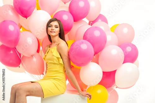 colorful portrait of young beautiful model with a lot of pink yellow and white baloons