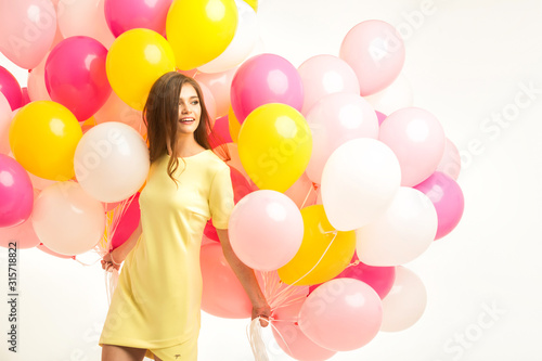 colorful portrait of young beautiful model with a lot of pink yellow and white baloons