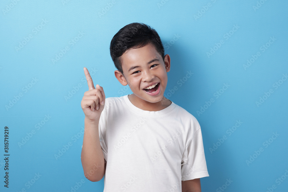 Happy Asian boy pointing finger up, having idea gesture Happy Asian boy pointing finger up, having idea gesture