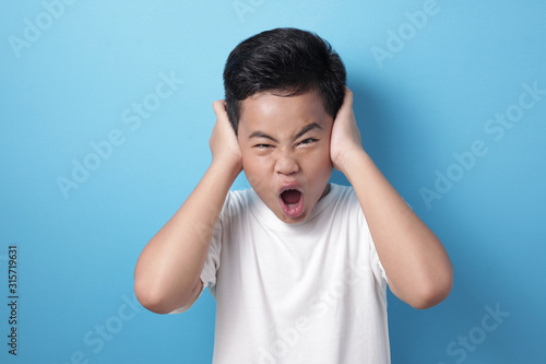 Asian boy screaming and close his ears, don't want to hear
