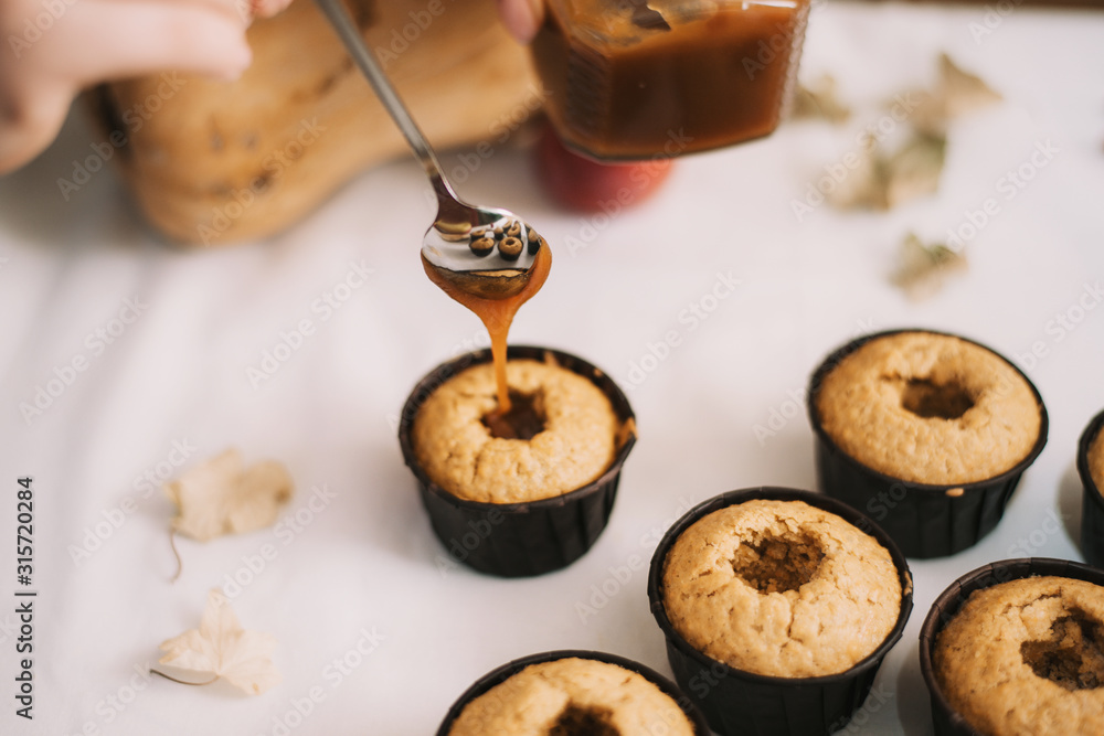The baker creates cupcakes in molds. Filling biscuits with homemade liquid caramel. Making homemade muffins The baker creates cupcakes in molds. Filling biscuits with homemade liquid caramel. Making homemade muffins