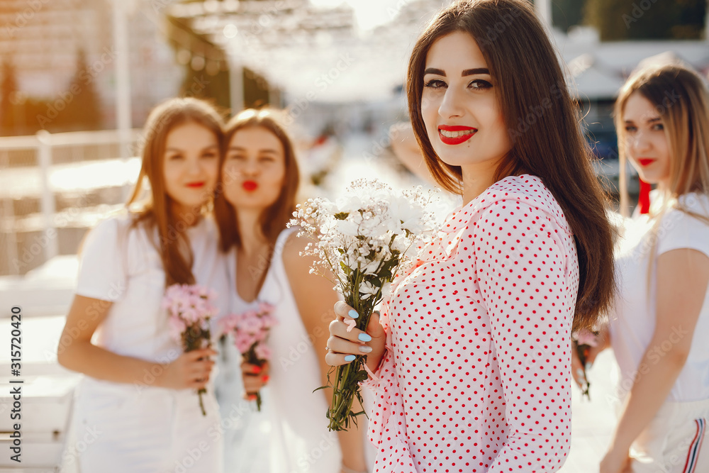 Beautiful girls with bouquet of flowers. Friends have fun in a summer park Beautiful girls with bouquet of flowers. Friends have fun in a summer park