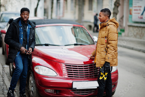 Two african male friends standing near red american convertible car. © AS Photo Family