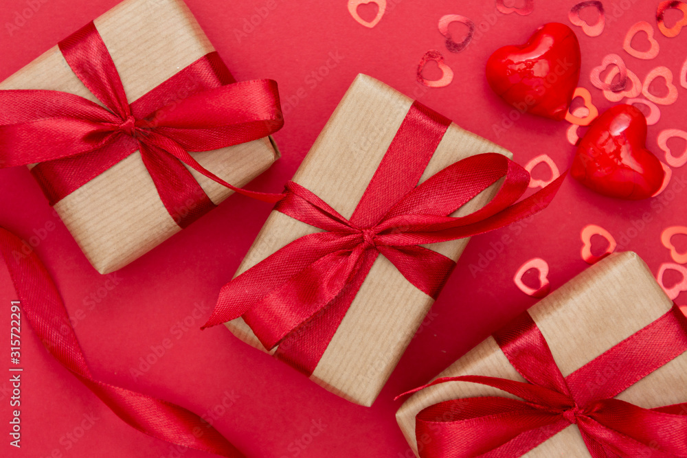 Gift box wrapped with kraft paper and red bow isolated on red background. Abstract flat lay. Gift box wrapped with kraft paper and red bow isolated on red background. Abstract flat lay.