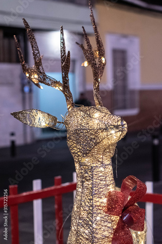 Cute glowing reindeer made of wire and light bulbs at the street. Decoration for Christmas celebration