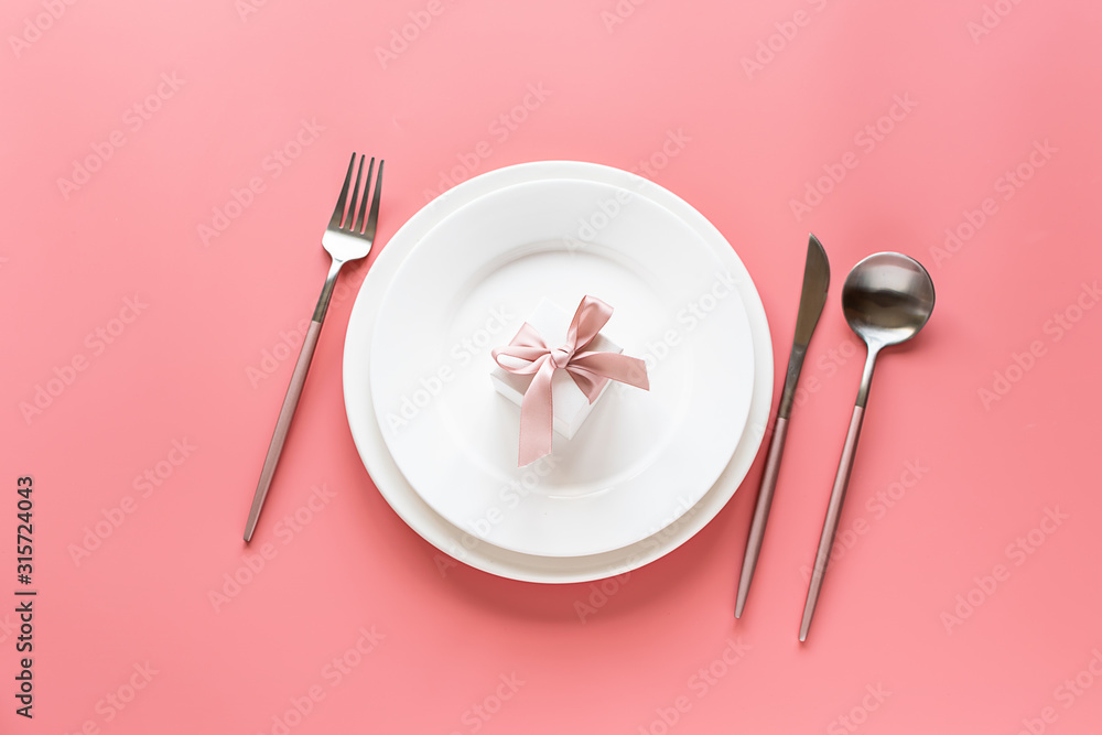 Fototapeta Flat lay overhead of festive table setting with white plates, pink cutlery and decor on trendy pink pastel background. Mothers Day composition. Valentines Day background.