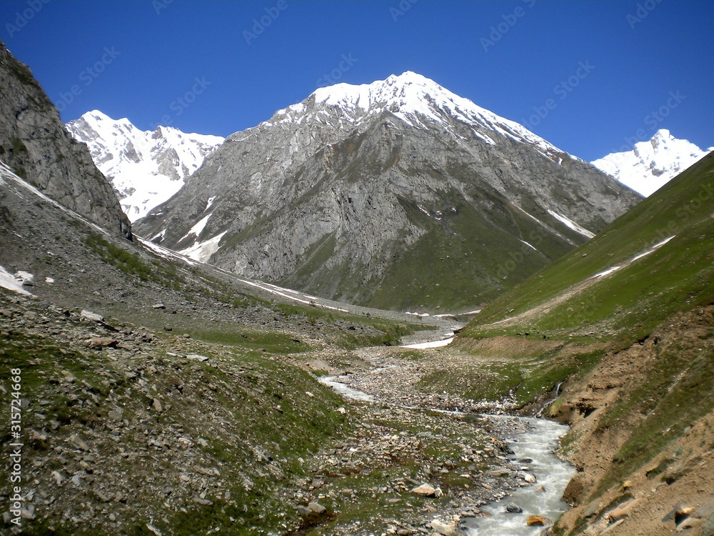 High mountain with green land and snow 