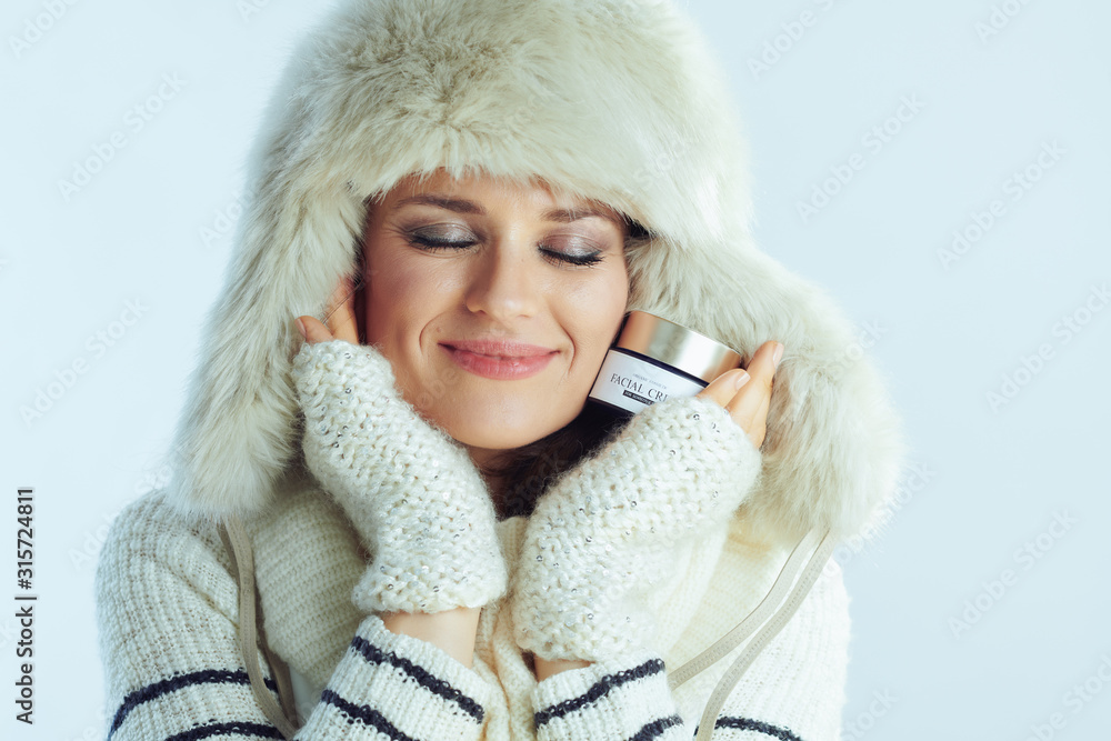 woman holding creme isolated on winter light blue background woman holding creme isolated on winter light blue background