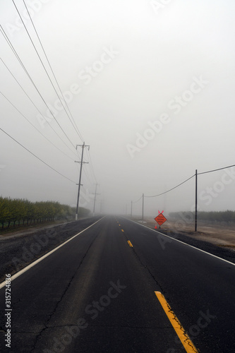 Foggy road with caution sign