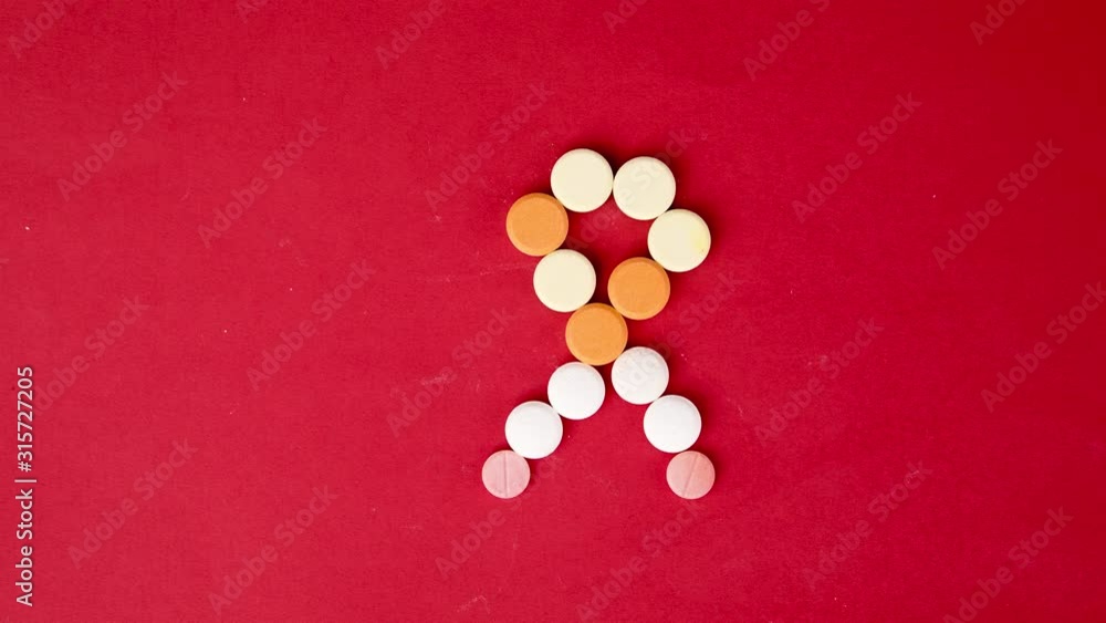 Top view stop motion of pills shaped awareness ribbon on red background in 4k resolution Top view stop motion of pills shaped awareness ribbon on red background in 4k resolution