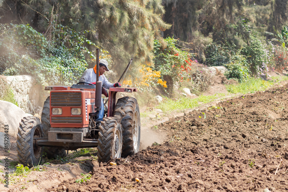 Obraz premium Man preparing the land for harvest with the tractor on the farm