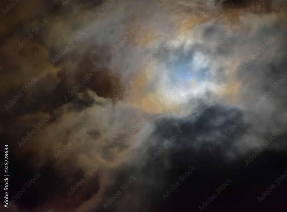 Cloudy night sky. Abstract photo with blurred clouds in very windy summer night. Interesting background with cloudy sky. The photo was taken at full moon. 