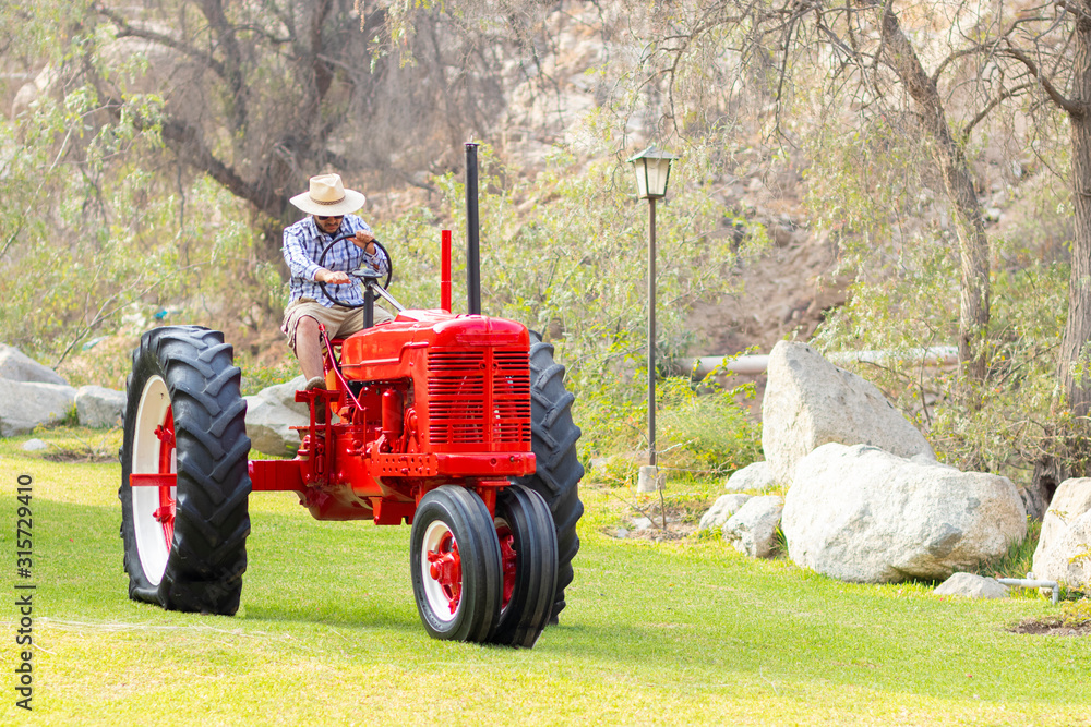 Obraz premium Handsome man with sunglasses driving the tractor to work on the farm