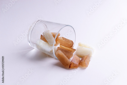 Spilled out ot of glass pieces of frozen icy coffee and milk on white background