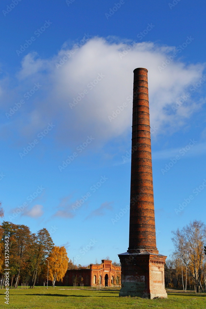 Antique single chimney. In the distance is a dilapidated arena building.