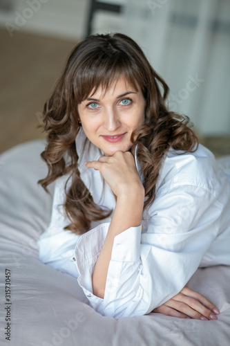  beautiful woman portred girl long hair smiling and sad in a white shirt in the bedroom on the bed photo