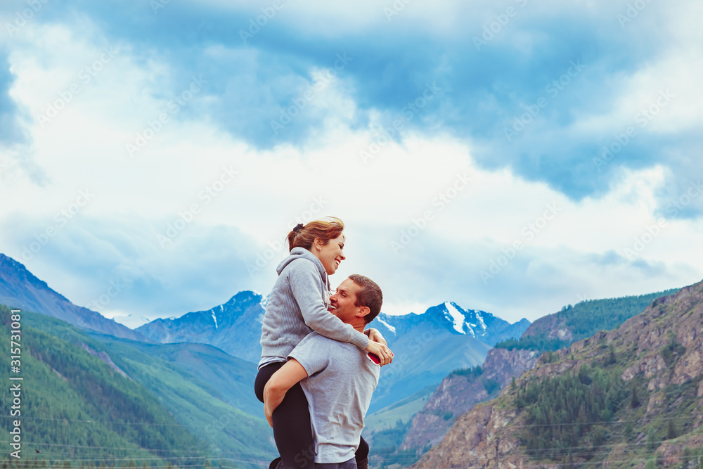 the couple stands against the background of mountains