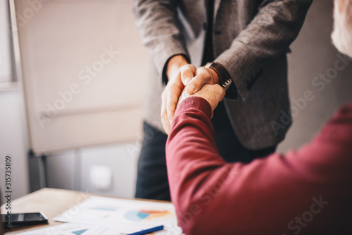 Two people shaking hands with selective focus at the hands.