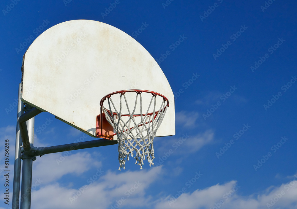 Basketball net in a wooden basketball hoop with blue sky and clouds Basketball net in a wooden basketball hoop with blue sky and clouds