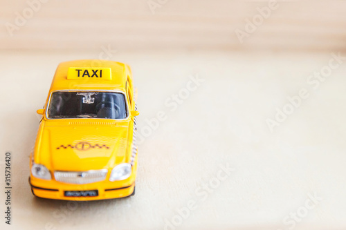 Simply design yellow vintage retro toy car Taxi Cab model on wooden background. Automobile and transportation symbol. City traffic delivery urban service idea concept. Copy space.