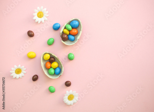 Chocolate Easter Eggs with colorful candies over pink background
