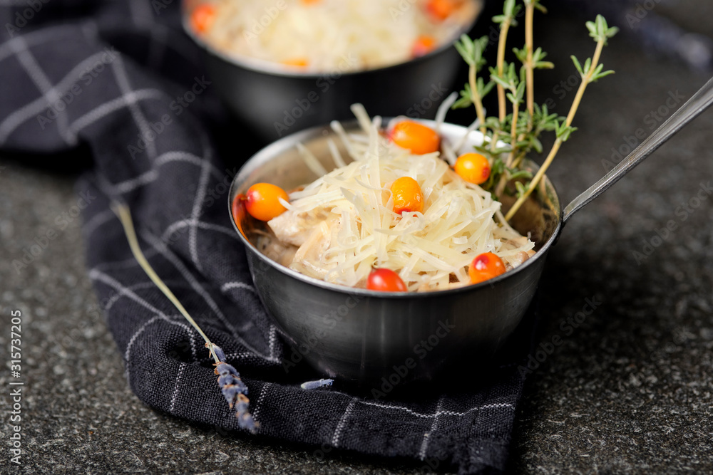 Festive french julienne with sea buckthorn in a bowl on napkin with bunch lavender on stone background. Rustic style. Baked mushroom julienne with chicken and cheese in pots. Top view. Close up