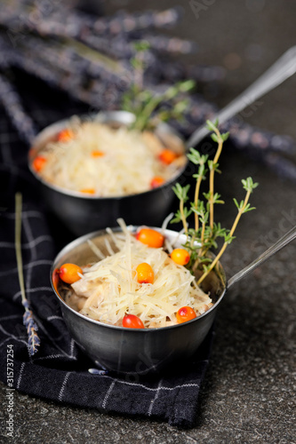Festive french julienne with sea buckthorn in a bowl on napkin with bunch lavender on stone background. Rustic style. Baked mushroom julienne with chicken and cheese in pots. Top view. Close up