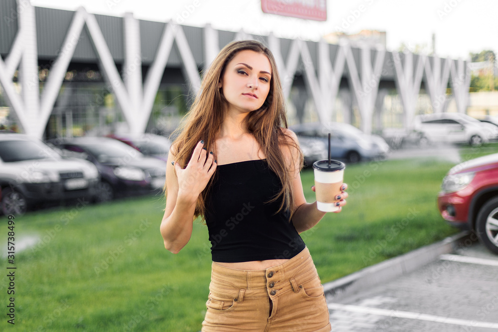 Beautiful young woman using phone and drink coffee walking on the street. Beautiful young woman using phone and drink coffee walking on the street.
