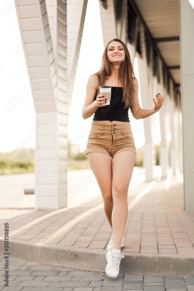 Beautiful young woman drink coffee and walking near the mall.