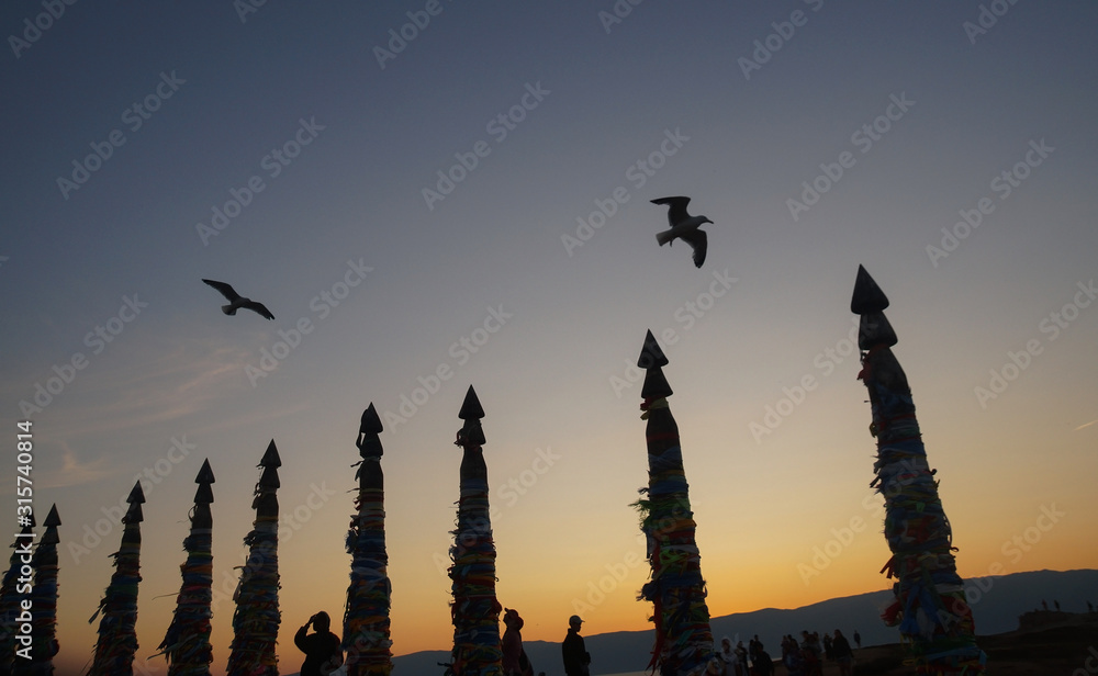 people and pillars on the background of the night sky with birds