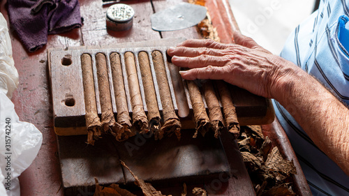 blue dressed man rolling / making handmade cigars in vinales, cuba