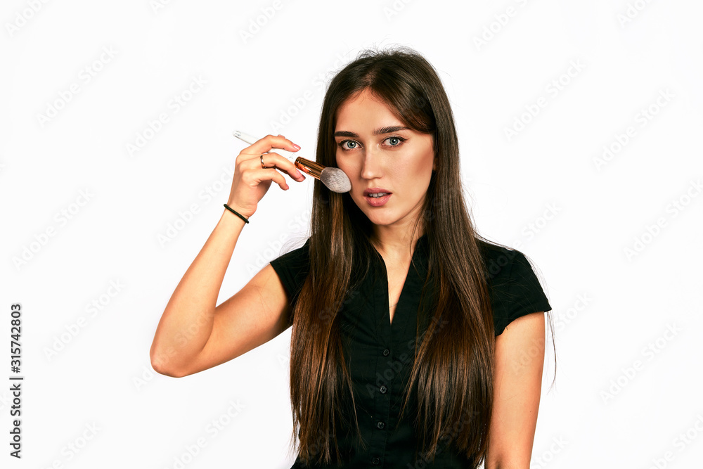 Professional makeup artist poses with the makeup brush and makeup products for advertising on white background. Professional makeup artist poses with the makeup brush and makeup products for advertising on white background.