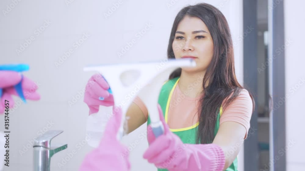 Pretty housewife cleaning a mirror in the bathroom at home. Shot in 4k resolution Pretty housewife cleaning a mirror in the bathroom at home. Shot in 4k resolution