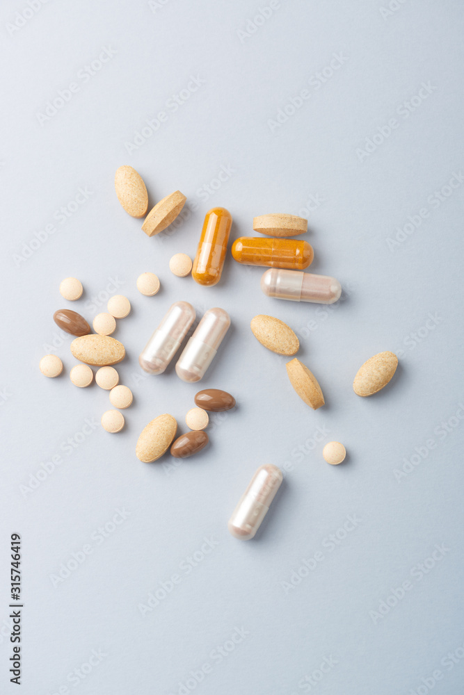 Multicolor vitamins and supplements on bright paper background. Concept for a healthy dietary supplementation. Top view. Multicolor vitamins and supplements on bright paper background. Concept for a healthy dietary supplementation. Top view.